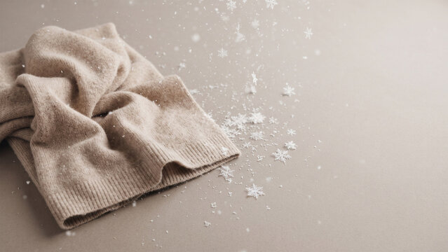 cozy cashmere knitwear with falling snow flakes on neutral background