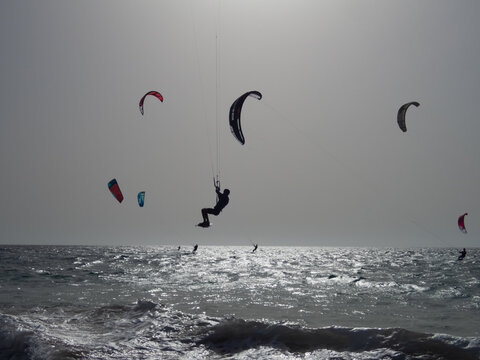 Kitesurfer Jumping Over Waves with Colorful Kites