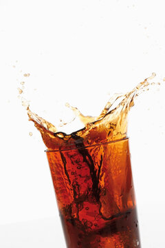 Ice cube falling in cola, close-up