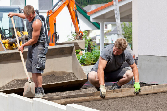 Germany, Rhineland Palatinate, Young men pulling smooth grit layer