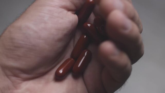 Closeup shot of medicine capsules being poured into open hand