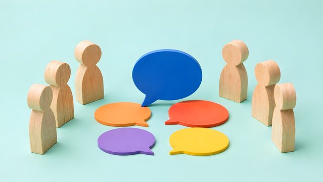 Wooden figures standing around colorful speech bubbles with one large blue bubble. Concept of diverse team brainstorming, multidisciplinary business meeting, and corporate communication.