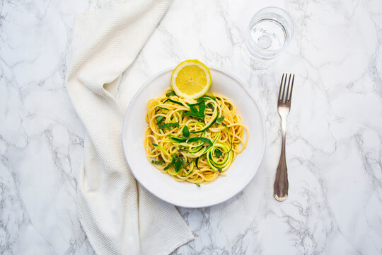 Lemon zucchini pasta with basil and mint sits on a marble table