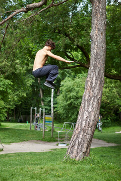 Germany, Bavaria, Young man doing parcour training in park