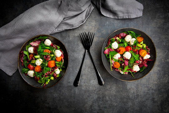 A black concrete table holds a fresh mozzarella salad
