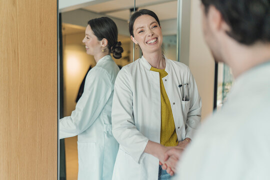 Smiling female doctor shakes hands with a man at private practice