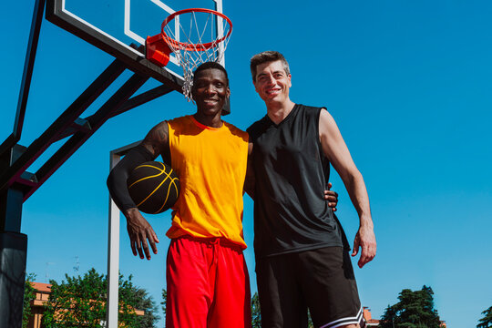 Two men hold a basketball on an outdoor urban court