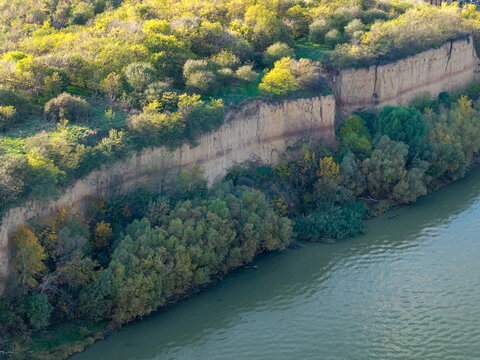 Aerial view of the right bank of the Danube River featuring steep loess cliffs covered in autumn foliage along the river in Surduk, Vojvodina, Serbia.