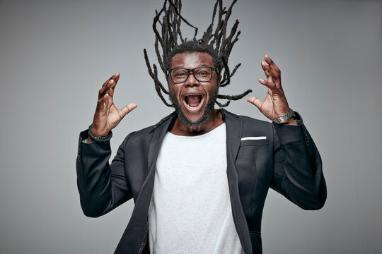 Portrait of screaming man tossing his dreadlocks