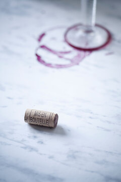 Red wine glass, stains and wine cork on white marble