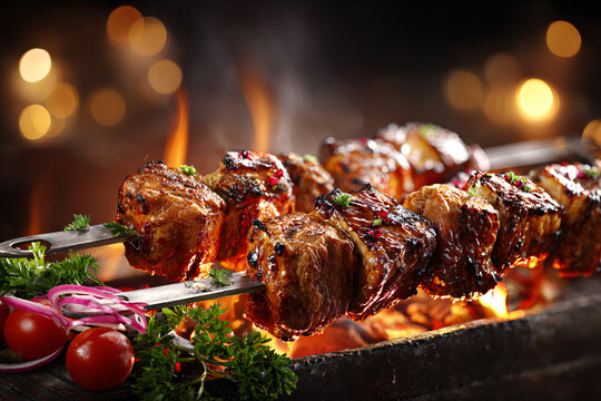 Juicy grilled meat skewers roasting over an open fire, served with tomatoes, red onion and fresh herbs