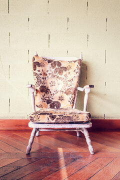 An old floral armchair sits on a wooden floor in Sagres Portugal