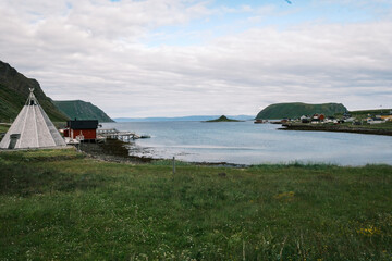Traditional white Sami lavvu tipi tent set up on the arctic tundra shore overlooking a coastal fjord on Magerøya island near Nordkapp, Norway. © Michele