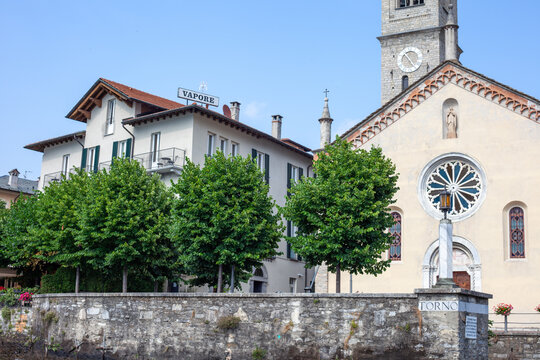 Torno, Lake Como, Italy Church and Hotel Vapore with Green Trees on the Lake Shore. Old Italian architecture. Como, Italy - June 24, 2026
