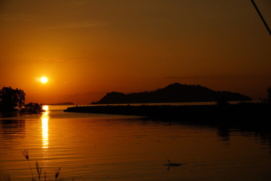 Orange Tropical Sunset Reflected Across Calm Coastal Water