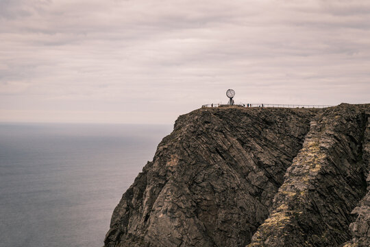 Wide horizon shot of the iconic metal Globe monument standing on the high precipice of North Cape above the endless Arctic Ocean in Norway.
