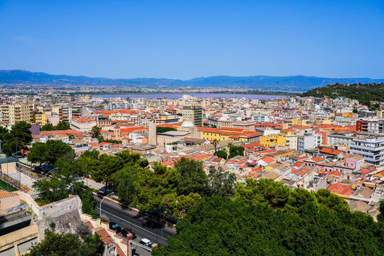 Aerial view over the rooftops of Cagliari towards the Molentargius-Saline Regional Natural Park lagoon and mountains, Sardinia, Italy