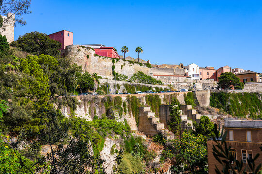 Historic stone fortifications and ancient ramparts of Castello district rising above lush greenery in Cagliari, Sardinia