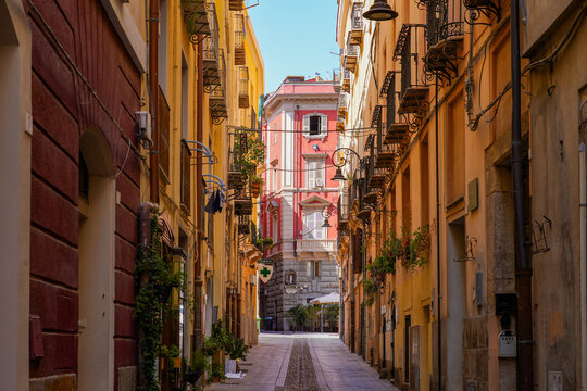 Narrow historic street lined with colorful traditional buildings and balconies in Cagliari, Sardinia