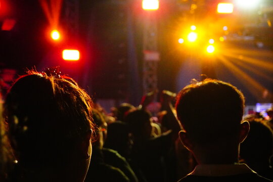 Concert Crowd Silhouettes Against Bright Orange Stage Lights