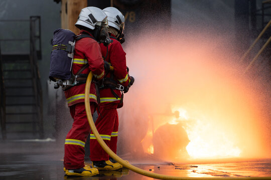 Firefighters in protective gear spray water to extinguish flames