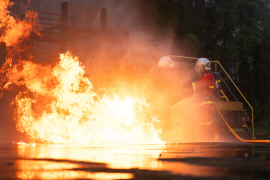 Firefighters in protective gear spray water to extinguish flames