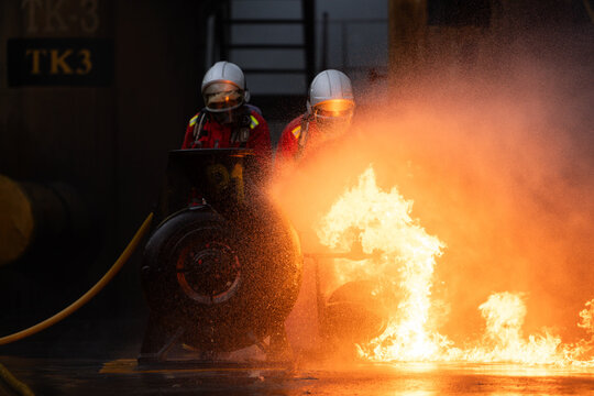 Firefighters in protective gear spray water to extinguish flames