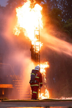 Firefighter wearing protective equipment operates a water hose