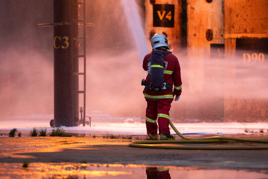 Firefighter wearing protective equipment operates a water hose