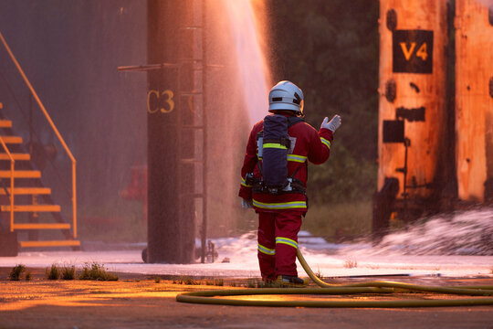 Firefighter wearing protective equipment operates a water hose