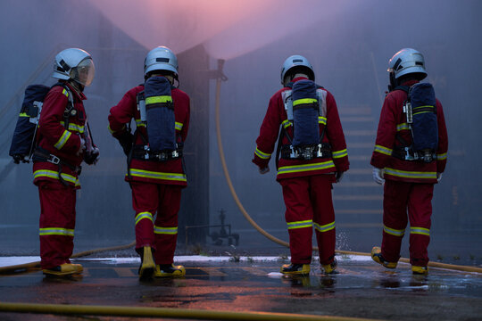 The four firefighters in protective gear walk through the remaining smoke and flames