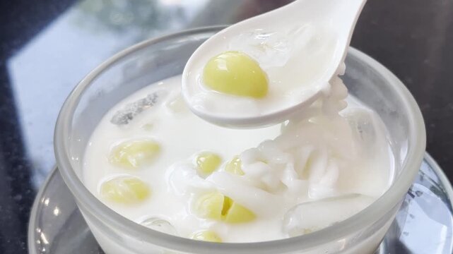 Close-up of chilled fresh milk with ginkgo nuts served in a glass bowl, showcasing a refreshing Asian dessert with a smooth and creamy texture.