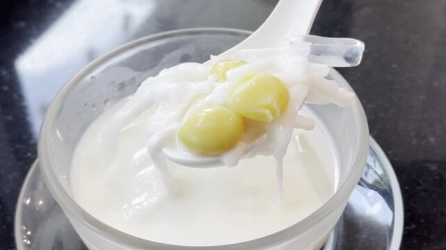 Close-up of chilled fresh milk with ginkgo nuts served in a glass bowl, showcasing a refreshing Asian dessert with a smooth and creamy texture.