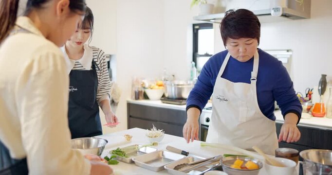 Women, chef and cooking traditional or Japanese food for teaching, class or learning. Female person, students and kitchen instruction to prepare ramen bowl for nutrition, travel or local experience