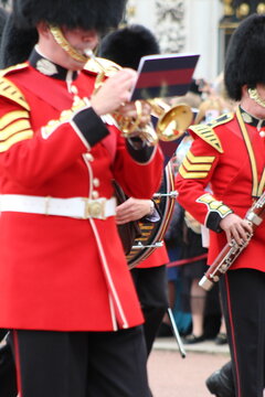 Aerial view of Queen's Guard soldiers in traditional red tunics and bearskin hats playing brass instruments during a ceremonial march in London, England, United Kingdom.