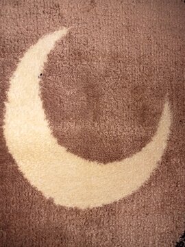 Crescent moon pattern on a soft brown textured rug or carpet surface