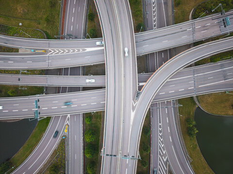 Aerial view of a complex highway interchange with multiple levels of roads, moving cars, and surrounding green spaces and water in Gothenburg, Vastra Gotaland County, Sweden.