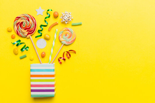 gift box in corner full of assorted traditional candies falling out on colored background with copy space. Happy Holidays sale concept