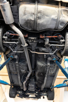 Full directly underneath view showing the chassis, drivetrain, exhaust system, and suspension of a car raised on a hydraulic lift.