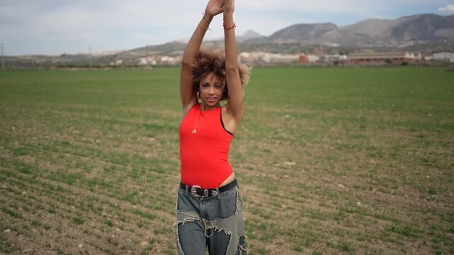 A fashionable woman enjoying her time in a beautiful scenic field landscape surrounded by nature