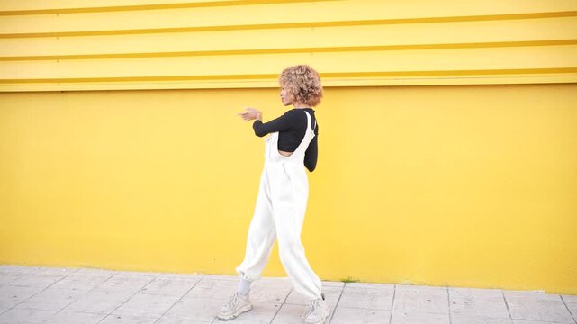 A Stylish and Young Woman Posing Confidently Against a Bright Yellow Wall in an Artistic Setting