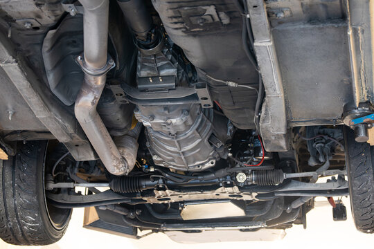Low angle view from below detailing the manual transmission casing, steering rack, exhaust downpipe, and front suspension.