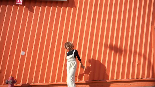 A Joyful Pose Captured in Front of a Bright and Vibrant Orange Wall, Full of Energy