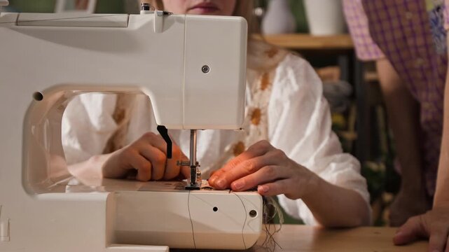 Midsection shot of woman operating sewing machine to stitch fabric in workshop. Clip is ideal for promoting handmade crafts, fashion design courses, or small tailoring businesses