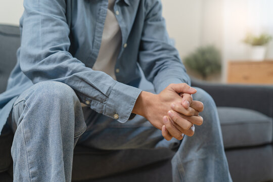 Stressed male feeling depressed and lonely on the sofa in the house.