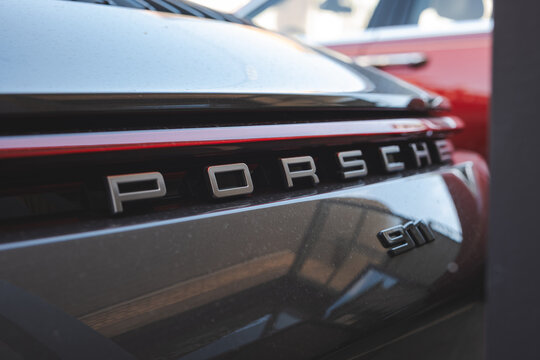 Lindau, Switzerland, August 9, 2026. Close up view of Porsche lettering and 911 badge on dark metallic rear bodywork.
