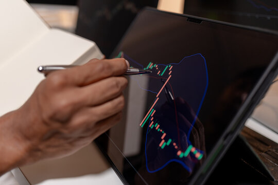 Professional trader analyzing stock market charts across multiple screens using laptop and tablet to monitor price movements, technical indicators and investment strategies in modern trading workspace