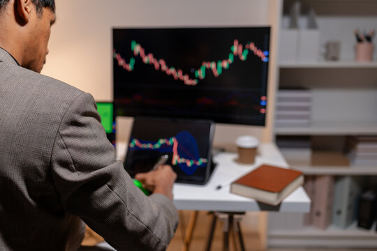 Professional stock trader reviewing market charts with sticky notes across multiple monitors, laptop, and tablet to analyze price trends, plan trading strategies, and manage investment decisions.