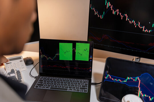 Professional stock trader reviewing market charts with sticky notes across multiple monitors, laptop, and tablet to analyze price trends, plan trading strategies, and manage investment decisions.