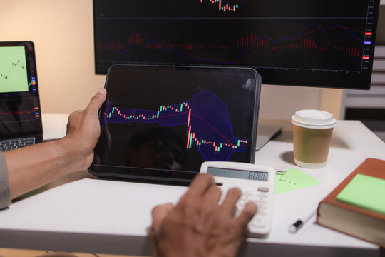 Professional trader analyzing stock market charts on laptop, tablet, and monitor while reviewing candlestick patterns, technical indicators, and market trends to support informed investment decisions.